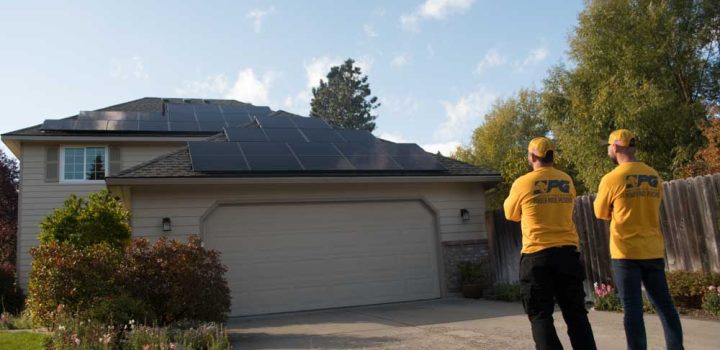 solar panel installer standing infront of a house with solar energy installed