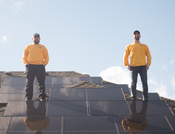 solar energy installation company owners standing on the roof with newly installed solar panels